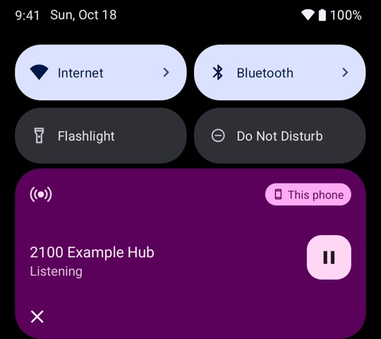 The media card in the Android quick settings. It shows 2100 Example Hub, Listening, with a pause button and This phone.